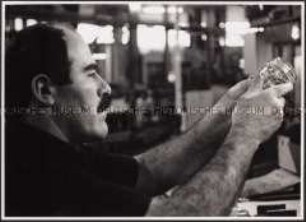 Türkischer Arbeitsnehmer in einer Glasfabrik schaut sich ein Glas an (Prämiertes Foto Sonderthema: Anders leben)