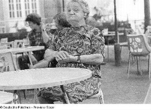 Alte Frau mit Hörgerät (in einem Straßencafé sitzend)