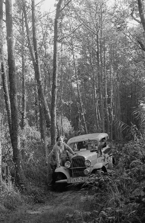 Roger Rössing aufgestützt auf einem Opel P4 im Wald