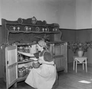 Arbeitsmaid beim Einräumen eines Geschirrschrankes in einem Lager der Reichsarbeitsdienstes