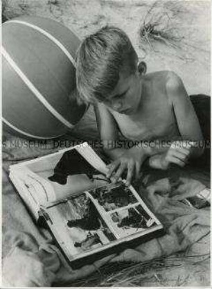 Junge liest ein Buch am Strand