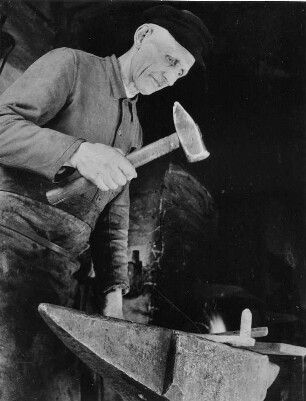 Ein niedersächsischer Dorfschmied bei der Arbeit. Das glühende Eisen wird mit dem schweren Schmiedehammer auf dem Amboss bearbeitet. Aufgenommen 1949