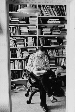 Der Schriftsteller Heinz Czechowski schreibend vor einem Bücherregal sitzend, aufgenommen in seiner Wohnung in Halle-Neustadt