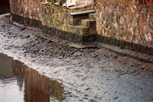 Fritz-Berodt-Straße 7-9: Hofanlage: Haus Nr. 7 [Haus am Teich]: Traufseite, Detailaufnahme: ehemalige Anlegestelle: Ufermauer mit Fundament, Teich bei Niedrigwasser: 10. Dezember 1993