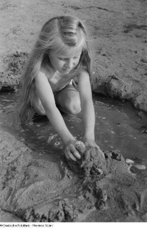 Mädchen, mit Sand spielend