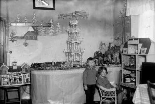 Kinder in der Weihnachtsstube mit Weihnachtsberg, Pyramide, Pferdestall und Puppenhaus