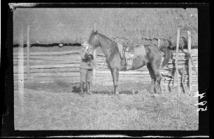 Pferd mit Burschen vor einem reetgedeckten Holzhaus