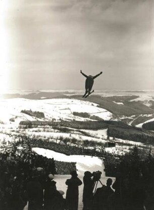 Osterzgebirge. Sachsenschanze am Geisingberg. Skispringen während der Deutschen Skimeisterschaften. Blick vom Schanzentisch mit Kamerateam und Springer nach Nordosten