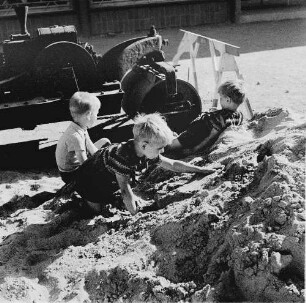 Dresden-Striesen, Borsbergstraße. Drei kleine Jungen spielen neben einer Dampfwalze in einem Sandhaufen