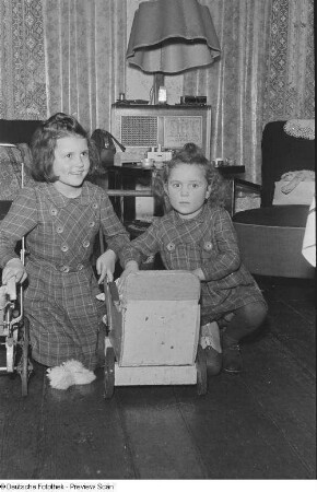 Porträt von zwei Mädchen mit Puppenwagen