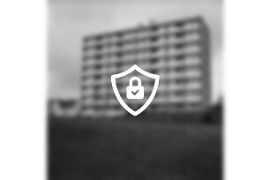 Hochhaus der Gemeinnützigen Wohnstättengenossenschaft eG Bad Oldesloe: davor Grünanlage und Spielgeräte