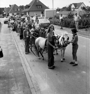 Dorffest der Dorfgemeinschaft Klein Wesenberg: Festumzug in Wohnstraße: im Vordergrund Anhänger mit Ponygespann. hinten Zuschauer, Pkws und Häuser