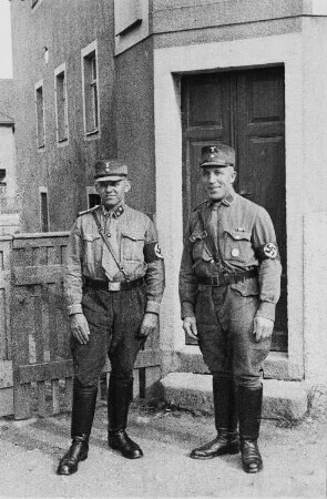 Angehörige der SA (Sturmabteilung) vor einem Hauseingang : auf den Mützen ist noch die bis 1936 getragene erste Form des Parteiadlers zu sehen