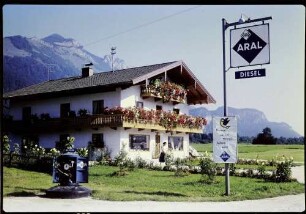 Schleching: Haus mit Blumenbalkon, Aralschild [Tankstelle]