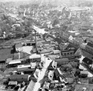 Vereinigte Molkereien Ahrensburg (Manhagener Allee): Luftbild des Betriebs: von rechts nach links verlaufend Manhagener Allee mit Bahnübergang, im Hintergrund Mitte Bahnstrecke Hamburg-Lübeck, im Hintergrund rechts Stormarnschule
