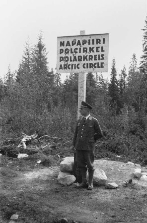 Am Polarkreis : Portrait eines Mannes vor einem Schild, das den Verlauf des Polarkreises kennzeichnet.