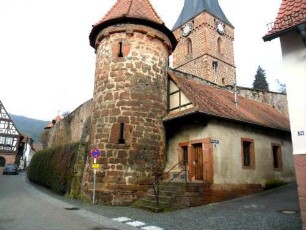Ansicht von Südosten mit Kirchturm (Chorturm) über Kirchhofmauer sowie Südost-Rundturm mit Schießscharten (Steigbügel-Scharten)