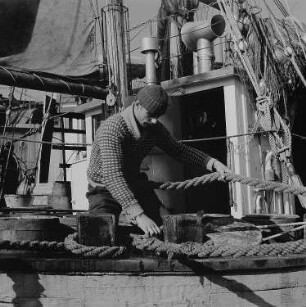 Stralsund. Fischereihafen, Fischer mit Tauen in einem Boot