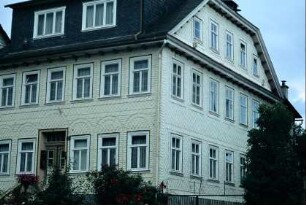 großes Haus mit weißen Schindeln (?), reichem Ornamentschmuck