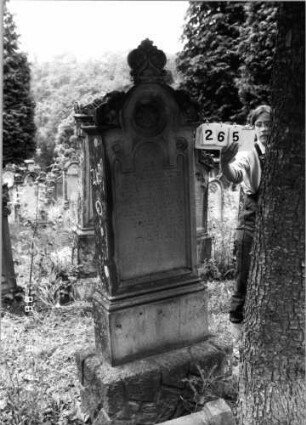 Grabstein 265 (Index: 100095781) Maße HxBxT: 189x57x23 cm Symbolik: Blumenkranz Besonderheit: kulturhistorisch wertvoll / hist.-wiss. Gründe (Gemeindestellung): Grabstein 265