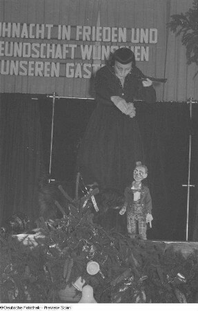 Eine Puppenspielerin mit einer Marionette in Gestalt eines Clowns auf einer Betriebsweihnachtsfeier