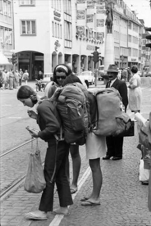 Freiburg: Englische Touristinnen mit Rucksäcken an der Haltestelle
