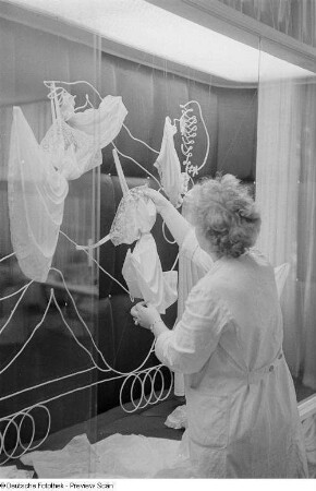 Eine Frau beim Dekorieren einer Vitrine der Leipziger Herbstmesse 1954 mit Damennachtwäsche