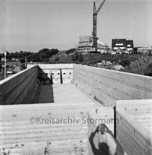 Zentralklärwerk: Anna-Heitmann-Weg: Richtfest für Faulturm und Vorklärbecken: Blick in Vorklärbecken, hinten Leiter: im Hintergrund Faulturm mit Gerüst, Baukran, Stapel mit Baumaterialien, Betriebsgebäude: im Hintergrund Wohnhaus: hinten links Autos an Weg,