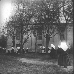 Burg (Spreewald). Frauen in Tracht beim Kirchgang vor der Pfarrkirche