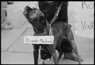 Hund auf einer Demonstration gegen die Staatssicherheit mit dem Schild "Nie wieder Maulkorb"