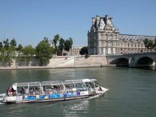 Seitenflügel des Louvre-Museums mit einem Touristenboot auf der Seine