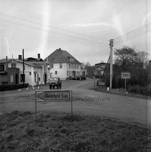 Ortseingang: Reinfelder Straße: vorn rechts Einmündung der Landstraße aus Richtung Zarpen mit Ortsschild: daneben Strommast: hinten Unimog: im Hintergrund Häuser