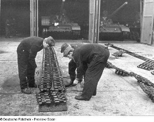 Goldberg (Kreis Lübz). Nationale Volksarmee - Landstreitkräfte. Panzerregiment 8 (PR-8). Freifläche vor Panzerhallen. Soldaten bei Instandsetzungs- bzw. Wartungsarbeiten an Gleisketten für Kampfpanzer T-54