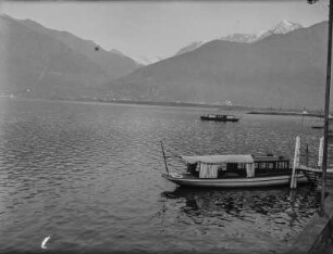 Seeblick : Blick über einen See, im Hintergrund Gebäude einer Stadt und Gebirge