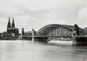 Köln, Hohenzollernbrücke : Köln. Eisenbahn- und Straßenbrücke (Hohenzollernbrücke) über den Rhein (1907-1911, F. Beermann, F. Dircksen; Steinbau u. Türme, F. Schwechten). Teilansicht (oberstrom) mit Dom vom rechten Ufer