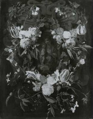Blumen um ein Steinrelief der Maria mit dem Kinde