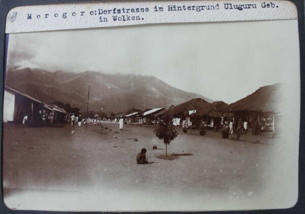 Morogoro: Village street in the background Uluguru building in clouds