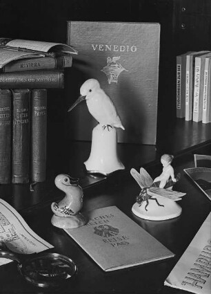 Putto auf Libelle : Stilleben mit Reiseführern (Mittelitalien, Unteritalien, Venedig, Paris u. a.), Keramikfiguren, Lupe und Reisepaß (wohl in der Wohnung der Fotografin)