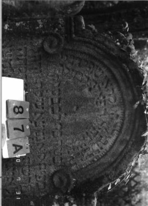 Grabstein 87 (Index: 99790580) Maße HxBxT: 128x88x17 cm Besonderheit: kulturhistorisch wertvoll / hist.-wiss. Gründe (Gemeindestellung): Grabstein 87A