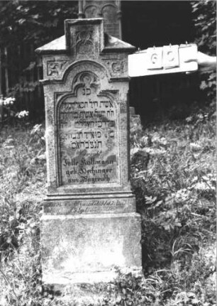 Grabstein 65 (Index: 100106527) Material: Sandstein Zustand: verwittert, teilweise Textverlust, Mittelaufsatz fehlt Maße HxBxT: 146x52x15 cm Beschreibung: Stele mit Walmdach, in der Mitte Rechteckerhöhung, Mittelaufsatz fehlt, Schriftfeld eingetieft in Maßwerkform, getreppter Sockel Besonderheit: kulturhistorisch wertvoll / hist.-wiss. Gründe (Gemeindestellung): Grabstein 65