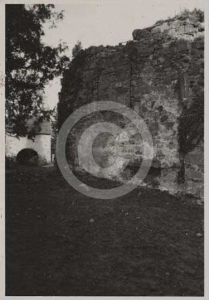 Mauer der Kirchenruine und Friedhofstor im Hintergrund Neukirch
