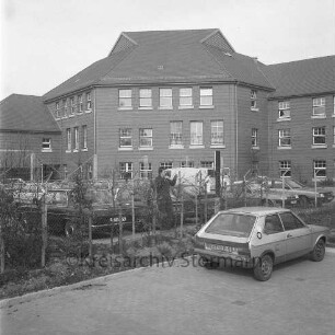 Amtsgericht: Königstraße: vor Einweihung: Außenaufnahme: Haupttrakt, Fassade zum Hof: davor Trenngitter: drei Maler, Farbeimer, Kleintransporter: Parkplatz, parkende Autos, Mann: im Vordergrund Maschendrahtzaun, Parkplatz, Pkw
