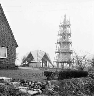 Rethwischdorf: Christuskirche: Rohbau: Außenansicht von Norden: Faltdachstuhl: davor Baubude: eingerüsteter Glockenturm zur Hälfte verschalt: vorn und links Wohnhaus mit Garten
