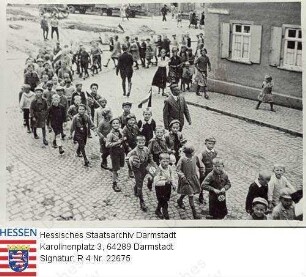 Nieder-Wöllstadt, 1934 um / Schulkinder, z. T. mit Hakenkreuzwimpeln, am Adolf-Hitler-Platz, Gruppenaufnahme