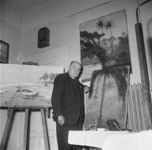 Marburg. Der Maler Prof. Ernst Vollbehr (1876-1960) in seinem Atelier vor seinen Gemälden stehend