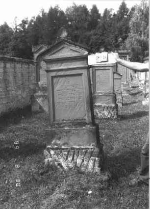 Grabstein 29 (Index: 99609665) Material: Sandstein Zustand: teilweise stark verwittert Maße HxBxT: 183x69x30 cm Beschreibung: Stele, Giebelabschluß mit Verdachung, Mittelpalmette, Schriftfeld eingetieft, getreppter Sockel, unten Rusticaimitat: Grabstein 29