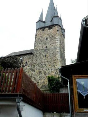 Evangelische Kirche - Kirchturm (frühgotisch 13 Jhd) von Norden mit Schießscharten in den Mittelgeschossen und Dach-Eckerkern auf dem Obergeschoß (ehemalige Wehrplattform)