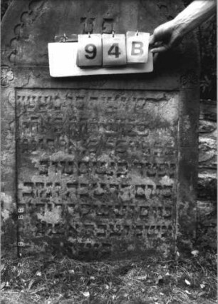 Grabstein 94 (Index: 100110777) Material: Sandstein Zustand: leicht verwittert mit einzelnen Abschieferungen, geringer Textverlust Maße HxBxT: 110x69x12 cm Beschreibung: Stele, Rundbogenabschluß mit Rundbogenfries, Schriftfelder eingetieft Symbolik: 4 Blüten: Grabstein 94B
