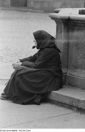 Porträt einer alten Frau an einem Brunnen