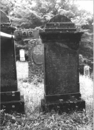 Grabstein 142 (Index: 99799444) Material: Sandstein Zustand: verwittert, zerbrochen und repariert Maße HxBxT: 158x64x22 cm Beschreibung: Stele, Abdeckplatte, mehrfach eingezogener Bogenaufsatz, Schriftfeld rechteckig erhaben, getreppter Sockel: Grabstein 142